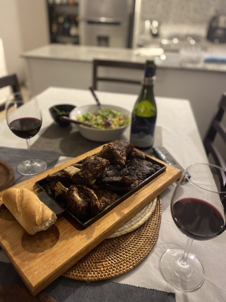 Maridaje de asado argentino con vino tinto y blanco en mesa familiar